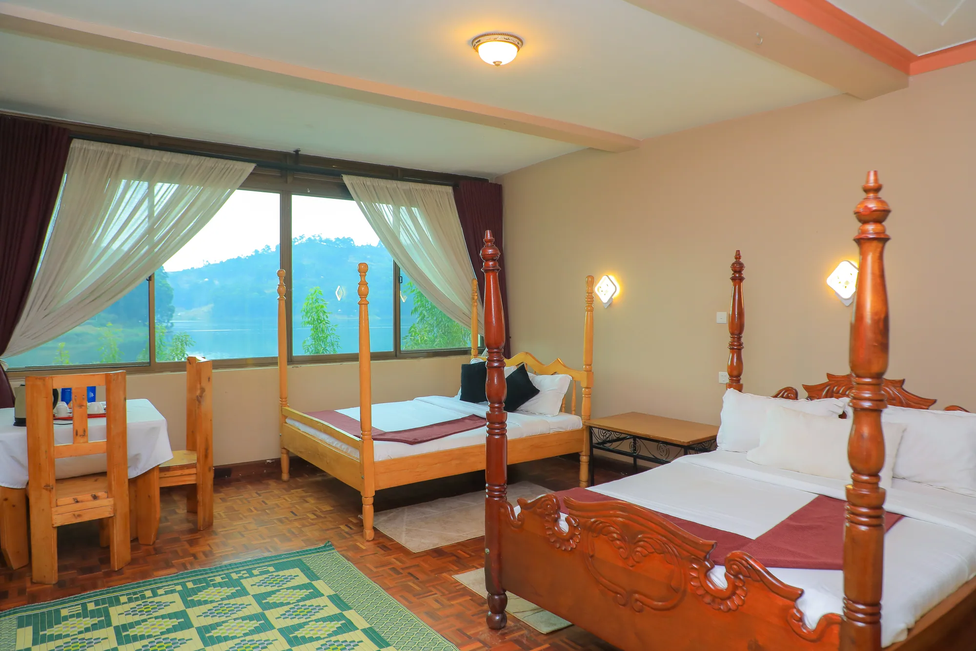 A triple room with three beds, a rug and windows looking to the hills