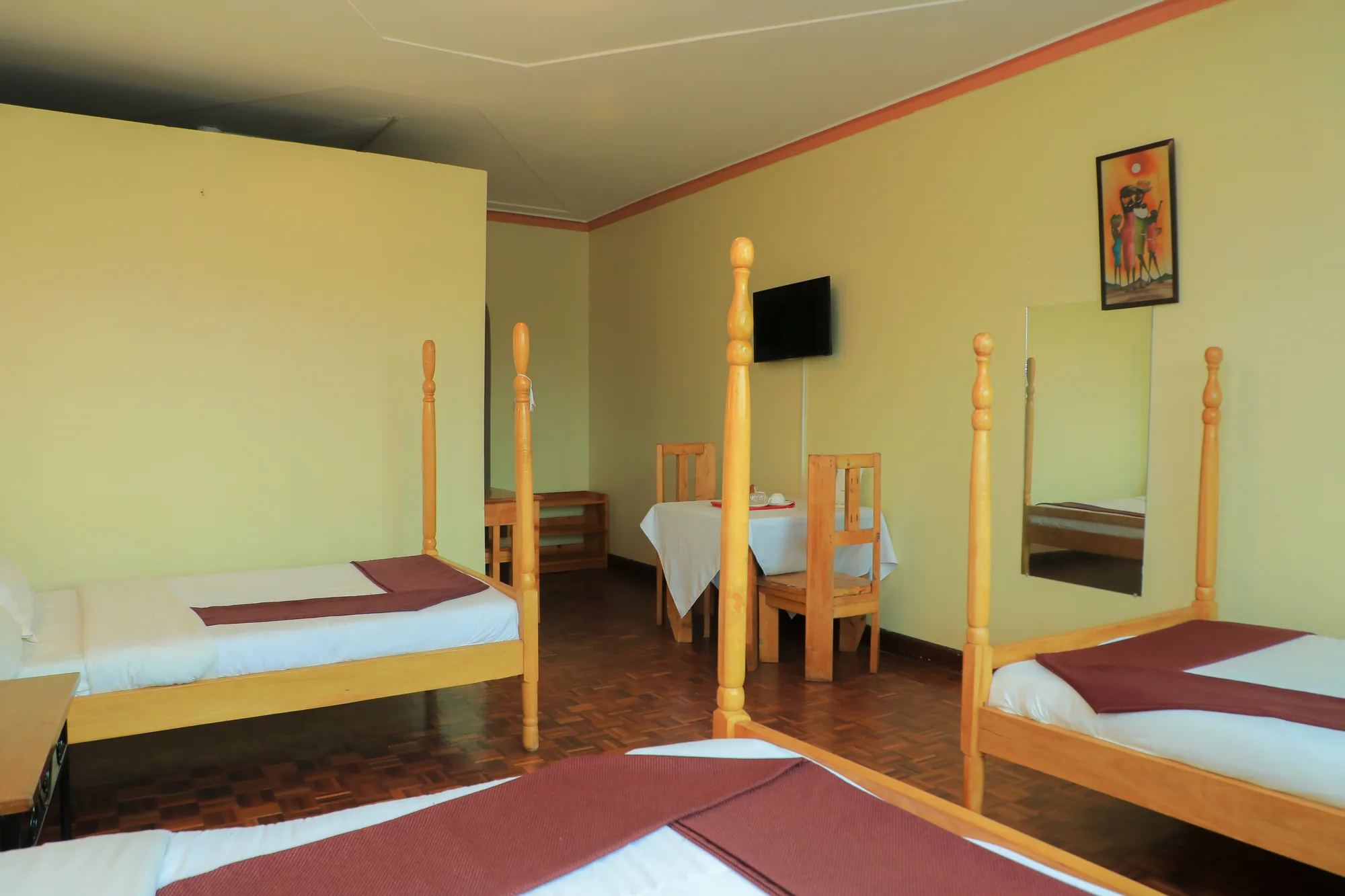 A twin room with pale walls, two beds, a table and chairs and a television