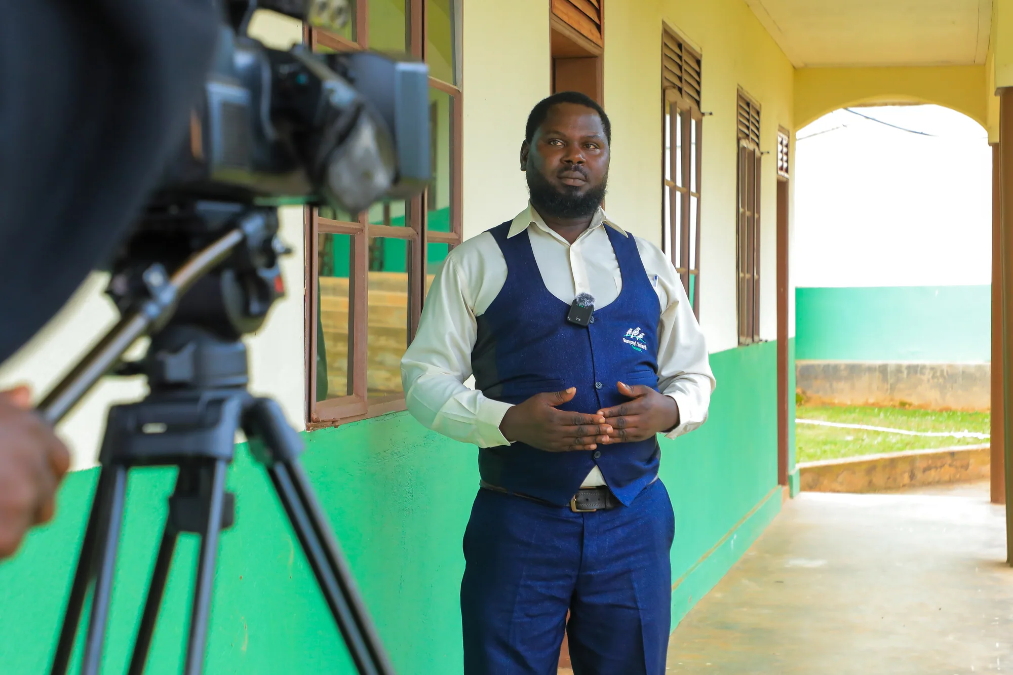 A staff member in a branded waistcoat being filmed on the institute veranda
