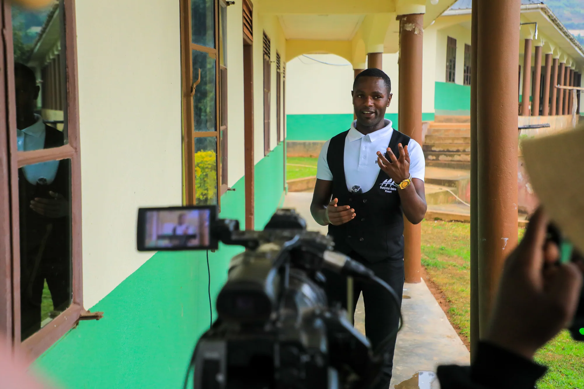 A staff member speaking to a video camera on the institute walkway