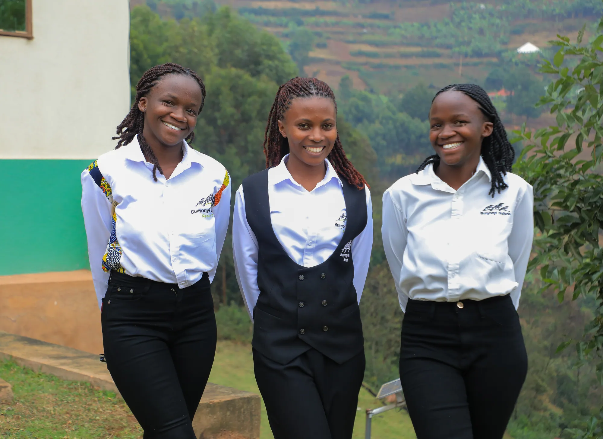 Three staff members in branded shirts walking together on the hillside path
