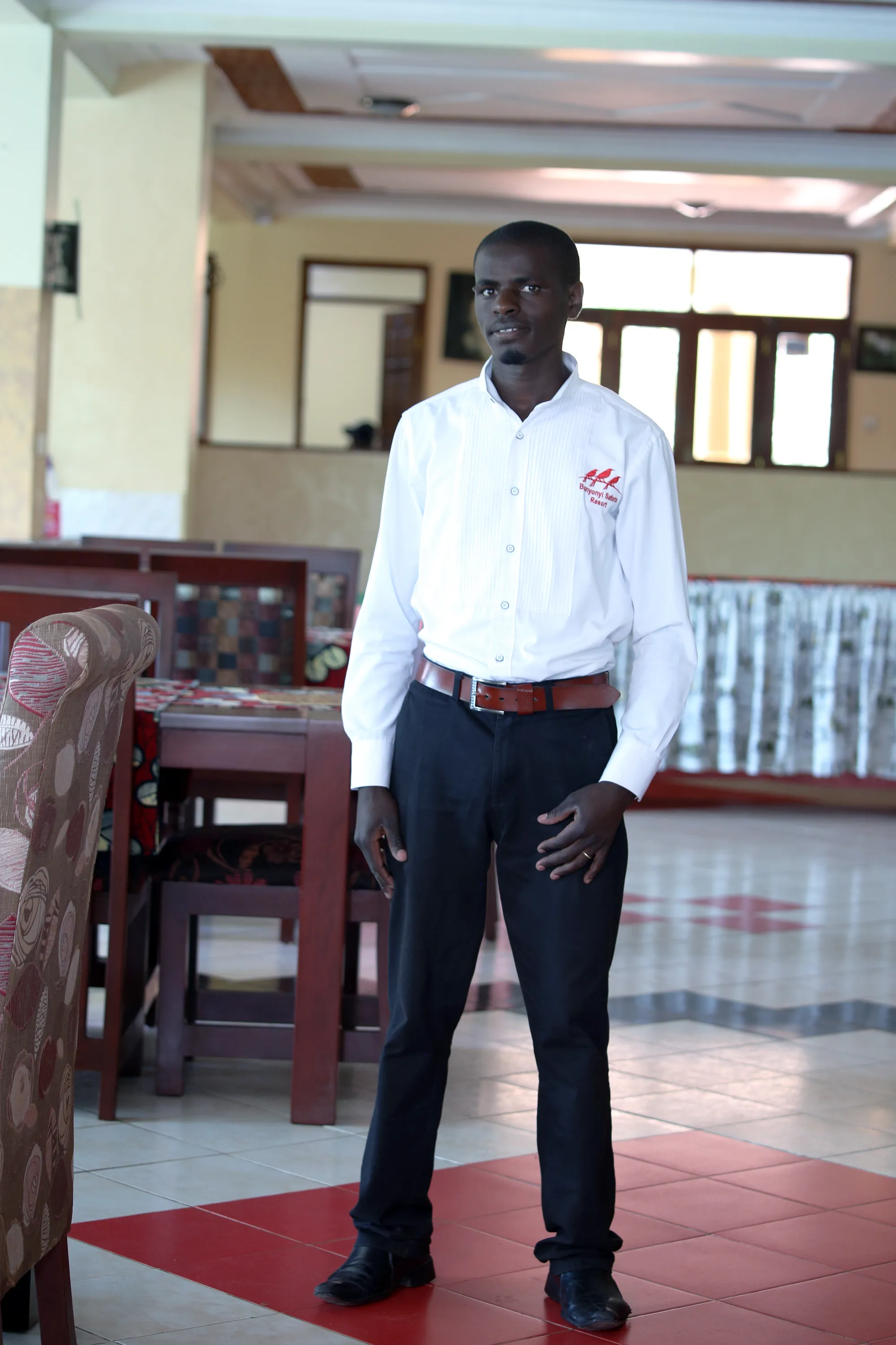 A staff member standing in the restaurant beside the timber chairs