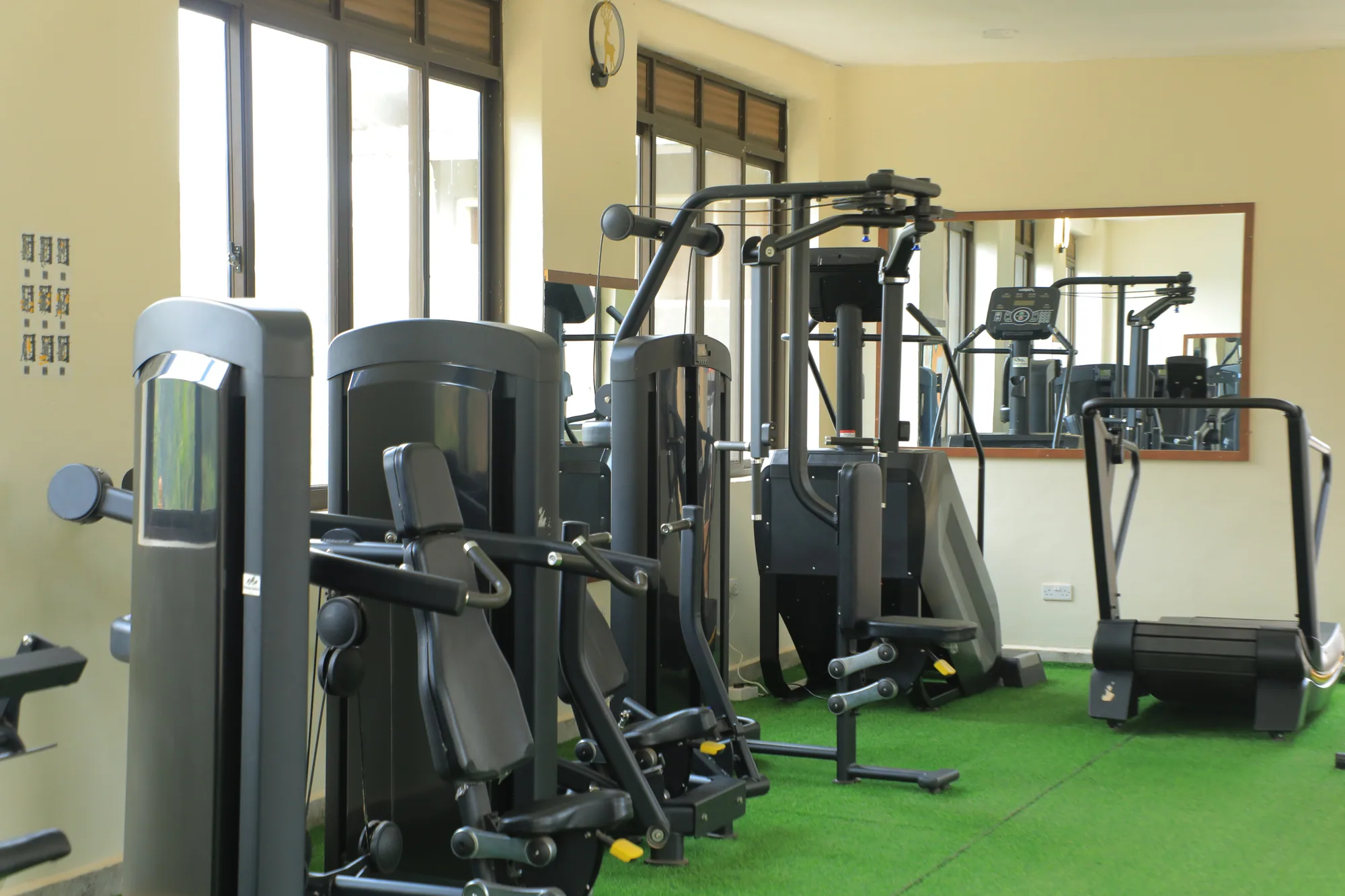 Weight machines and a treadmill along the gym wall beside a mirror