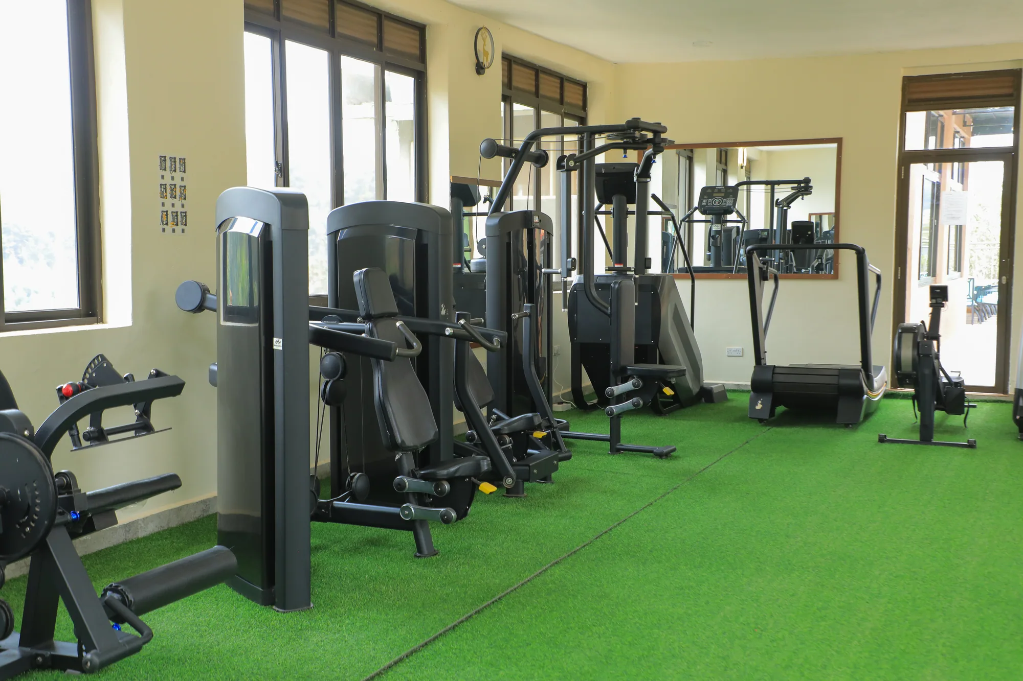 Weight machines along the gym wall with the mirrored corner beyond