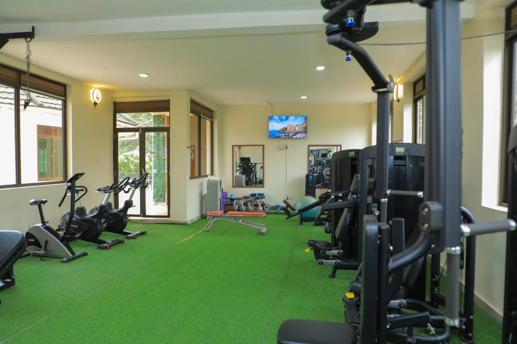 The gym from the doorway, exercise bikes and a wall-mounted screen at the far end