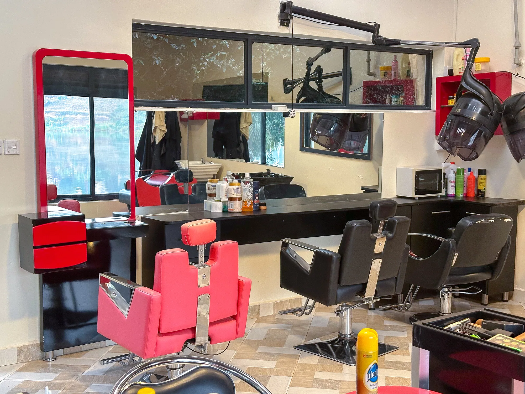 The salon with red barber chairs, mirrors and a trolley of products
