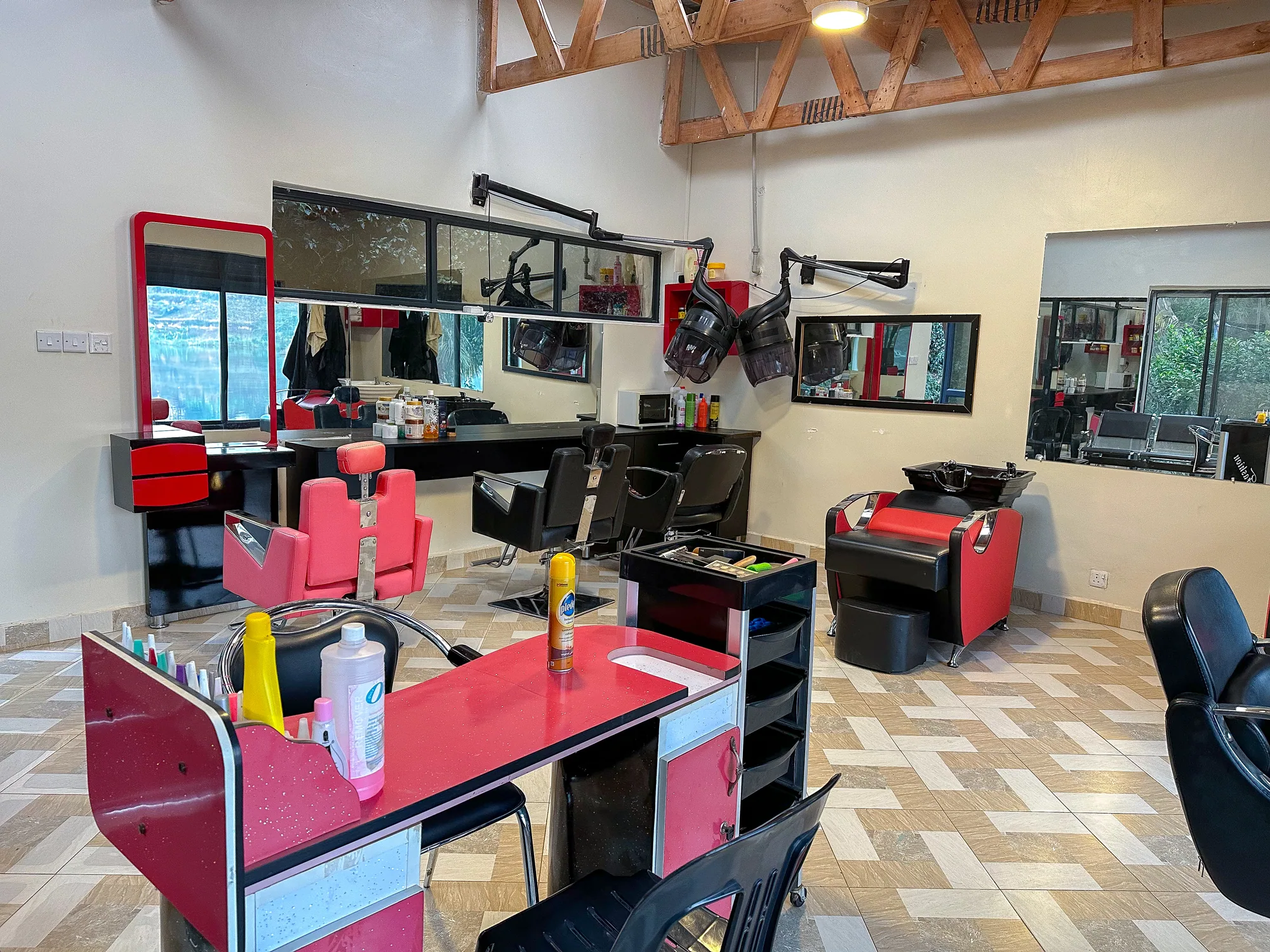 A pink and mirrored styling station with red chairs in the salon