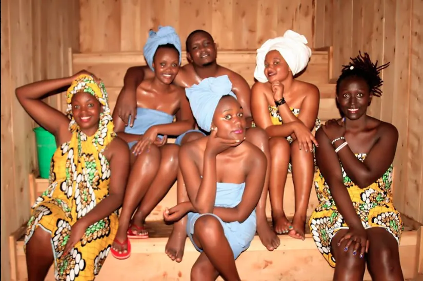 A group of guests wrapped in towels sitting on the sauna benches
