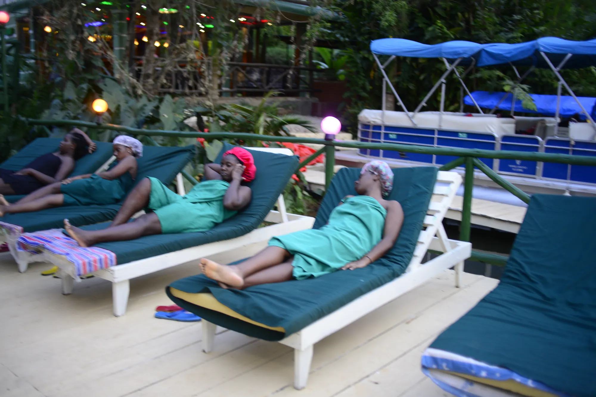 Guests wrapped in towels resting on sun loungers on the deck in the evening